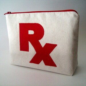 May include: A white canvas zippered pouch with a red embroidered "Rx" on the front.