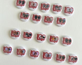 May include: A collection of white round buttons with a red heart and the words "I" and "MY BOYFRIEND" printed on them. Each button features a photograph inside the heart. The buttons are arranged on a white surface.