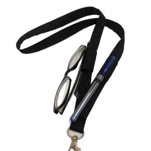 May include: Black lanyard with a silver clasp, holding a pair of eyeglasses and a pen. The lanyard has a pocket for the pen and a slot for the glasses. The eyeglasses have black frames.