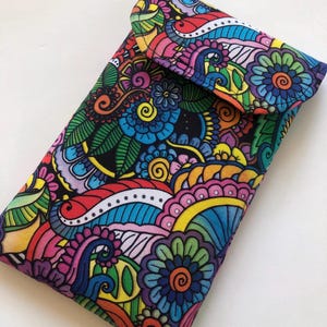 May include: A colorful fabric glasses case with a flap closure. The case features a vibrant floral pattern in shades of blue, green, pink, yellow, and red against a black background. The design includes stylized flowers, leaves, and swirling patterns.