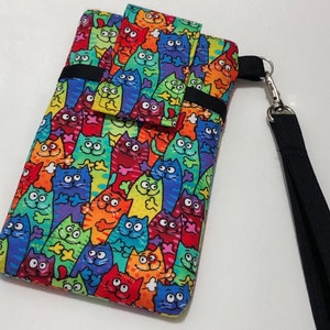 May include: A colorful phone case with a pattern of cartoon cats. The case has a black strap and a small pocket on the front.