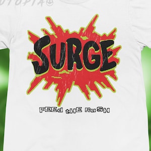 May include: White t-shirt with a distressed red and yellow graphic that says "SURGE" in black block letters. Below the graphic, the text reads "FEED the RuSH". The shirt is a crew neck.