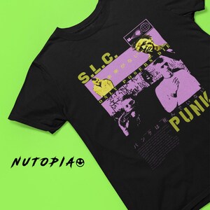 Op de afbeelding: Zwart T-shirt met een grafische print van een band genaamd "S.L.C." met de tekst "Only Posers Die" en Japanse tekst. De grafiek is in roze, geel en wit.