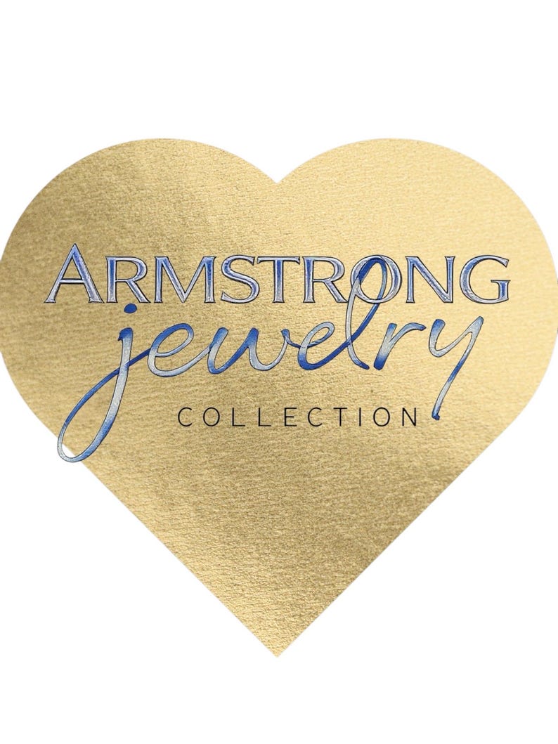 May include: A gold heart-shaped logo with the text "ARMSTRONG jewelry COLLECTION" in blue script. The heart has a textured, metallic appearance, and the text is in a stylized font, suggesting a jewelry brand.