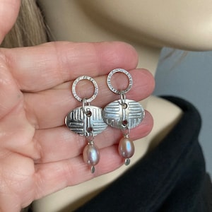 Glossy, rose colored drop Pearls hang from a patterned Fine Silver oval and hand textured, Sterling mini hoops, post style, dangle earrings.