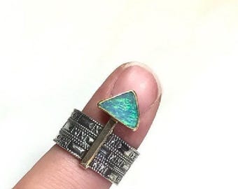 May include: A silver ring with a textured band and a triangular opal gemstone set in gold. The ring is on a finger.