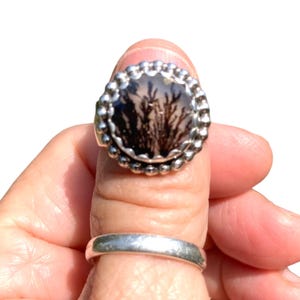 Puede incluir: Un anillo de plata con una piedra de &aacute;gata dendr&iacute;tica negra y blanca engastada en un engaste de cuentas.