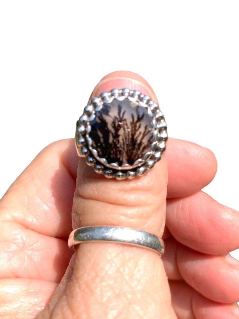 Puede incluir: Un anillo de plata con una piedra de &aacute;gata dendr&iacute;tica negra y blanca engastada en un engaste de cuentas.