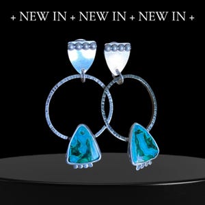 May include: Silver earrings with turquoise and green triangular stones, and a textured hoop design. The earrings have a shield-shaped top with small silver beads. The words "+ NEW IN + NEW IN + NEW IN +" are at the top.