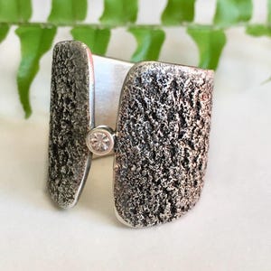 Stylish, torch textured Sterling silver ring bridged with a sparkling Sapphire gemstone, size 7.5. One of a kind artisan designed ring band.