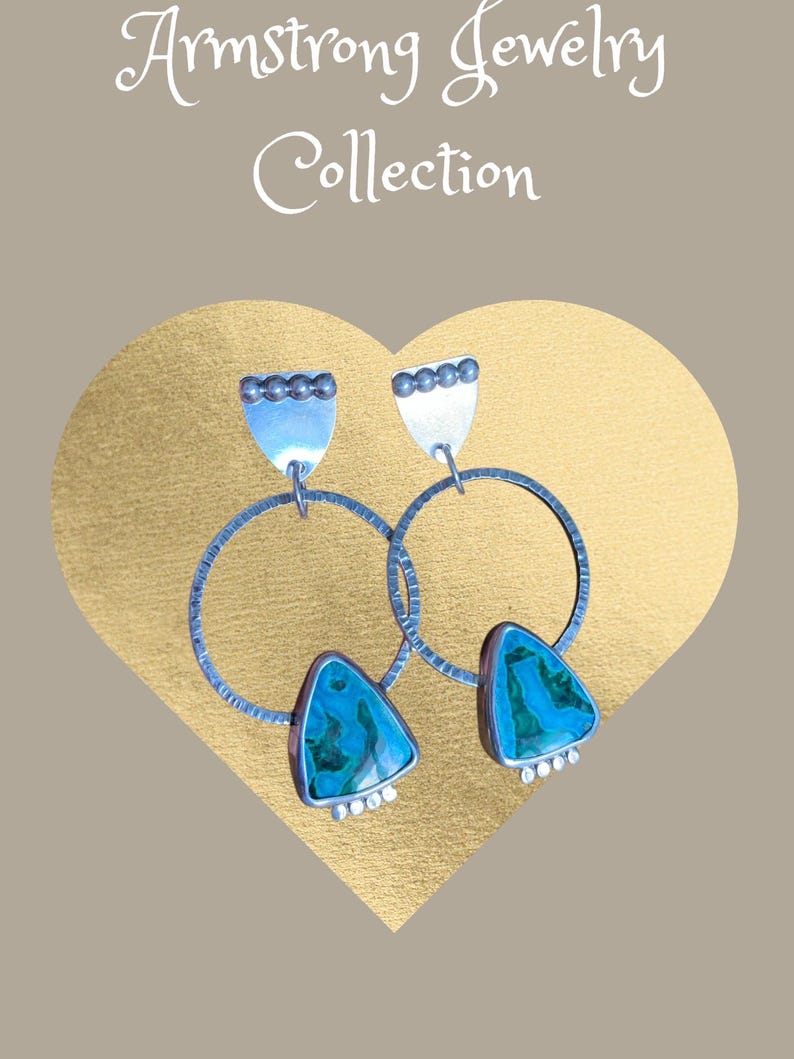 May include: A pair of silver earrings from the Armstrong Jewelry Collection. Each earring features a large silver hoop, a triangular turquoise stone, and a silver top with small silver beads. The background is a gold heart shape.