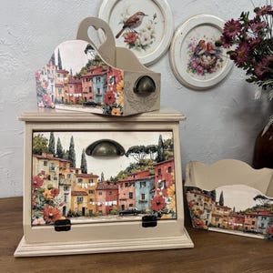 May include: A decorative wooden storage box, letter holder, and two framed bird prints. The box and holder feature a colorful Italian village scene with red, orange, and yellow flowers. The prints depict birds and floral arrangements.