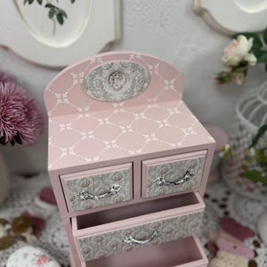 Handcrafted wooden dresser-style jewelry and craft organizer with pink and gray tones, decorated with hand-painted roses, featuring a textured surface and acrylic lacquer finish — perfect as a gift for mom, sister, or daughter.