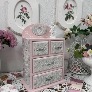Handcrafted wooden dresser-style jewelry and craft organizer with pink and gray tones, decorated with hand-painted roses, featuring a textured surface and acrylic lacquer finish — perfect as a gift for mom, sister, or daughter.