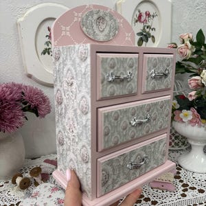 Handcrafted wooden dresser-style jewelry and craft organizer with pink and gray tones, decorated with hand-painted roses, featuring a textured surface and acrylic lacquer finish — perfect as a gift for mom, sister, or daughter.
