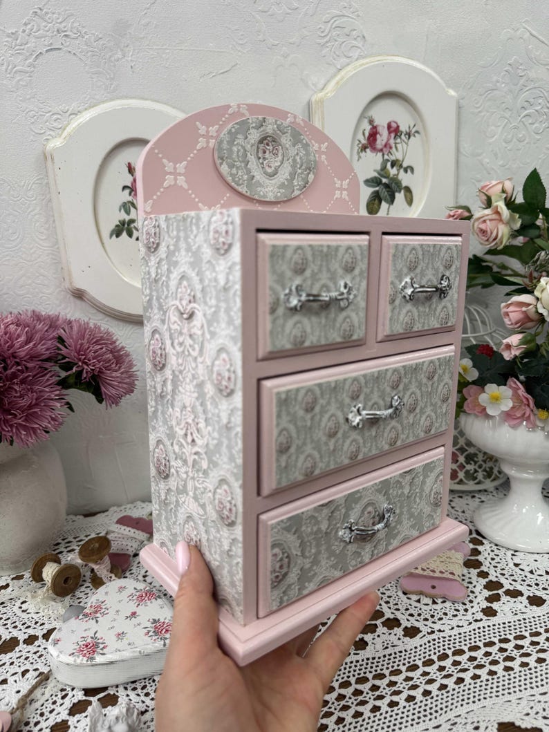 Handcrafted wooden dresser-style jewelry and craft organizer with pink and gray tones, decorated with hand-painted roses, featuring a textured surface and acrylic lacquer finish — perfect as a gift for mom, sister, or daughter.