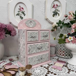 Handcrafted wooden dresser-style jewelry and craft organizer with pink and gray tones, decorated with hand-painted roses, featuring a textured surface and acrylic lacquer finish — perfect as a gift for mom, sister, or daughter.
