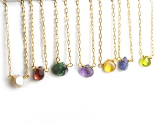May include: A set of 10 delicate gold necklaces with various gemstone pendants, including a pearl, amethyst, emerald, ruby, citrine, sapphire, and peridot.