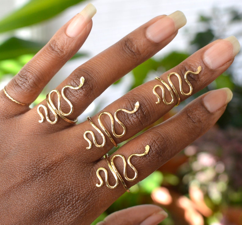 Puede incluir: Un conjunto de cuatro anillos de serpiente dorados que se llevan en los dedos de una mano. Los anillos est&aacute;n hechos de un metal delgado y flexible y est&aacute;n dise&ntilde;ados para envolverse alrededor del dedo.