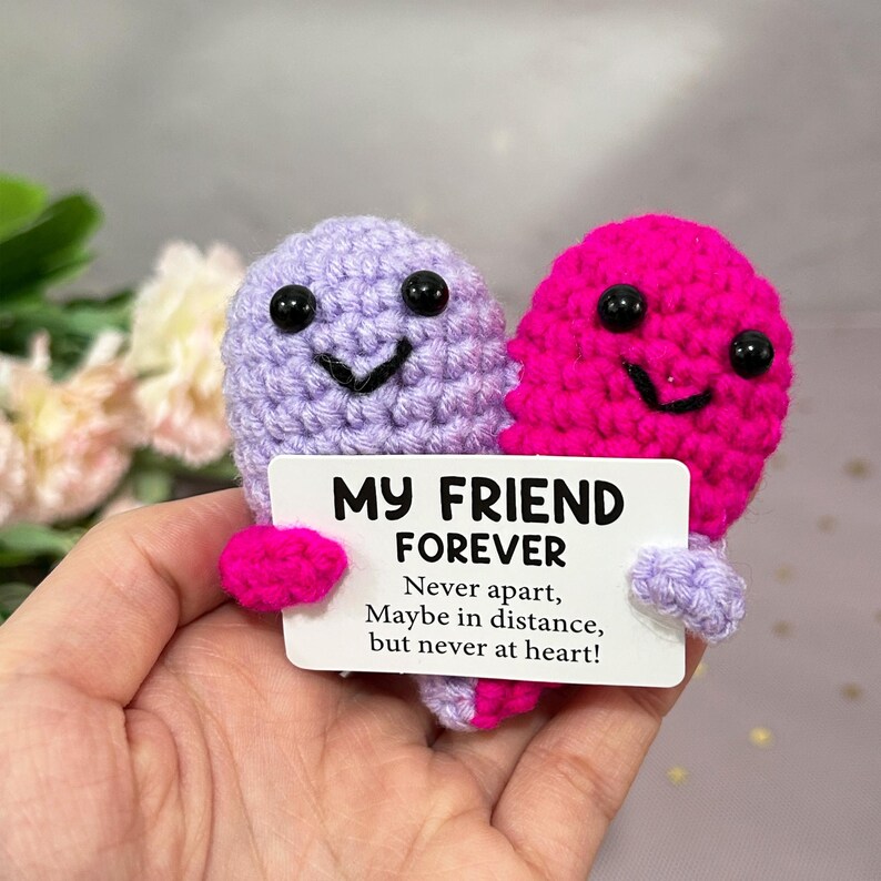 May include: A handmade crochet friendship gift featuring two smiling heart-shaped figures, one lavender and one fuchsia, holding a card. The card reads "MY FRIEND FOREVER" with a heartfelt message. A unique, sentimental gift.