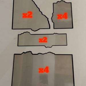 May include: A collection of five flat, rectangular, and irregularly shaped gray panels with black borders. The panels are marked with red text indicating quantities: two x2 labels and three x4 labels, denoting the number of pieces for each shape.