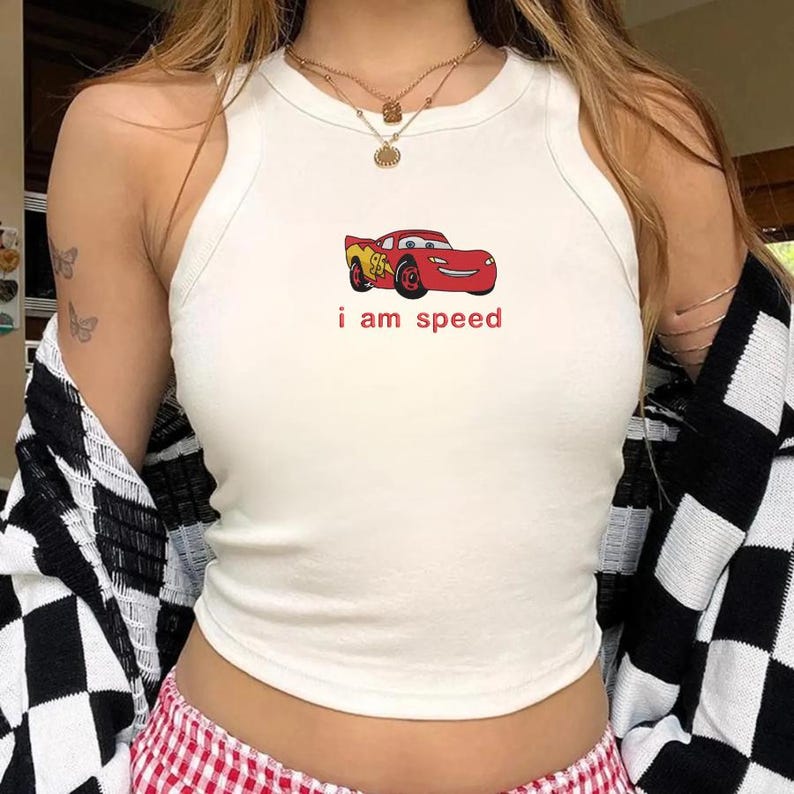 May include: White tank top with a red cartoon car graphic and the text "i am speed". The car is red with yellow accents. The top is a racerback style.