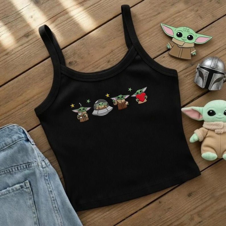 May include: Black spaghetti strap tank top with embroidered cartoon images of a green alien character. The tank top is paired with a pair of blue denim jeans. Additional character-themed accessories are also visible.