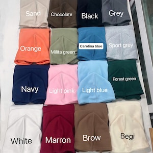 May include: A collection of fleece balaclavas in various colors, including sand, chocolate, black, grey, orange, milita green, carolina blue, sport grey, navy, light pink, light blue, forest green, white, marron, brow, and begi. Each balaclava is labeled with its color.