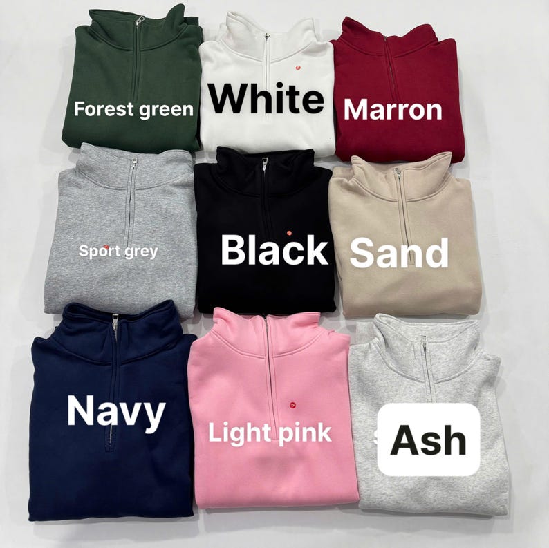 May include: A collection of nine quarter-zip sweatshirts in various colors, including forest green, white, maroon, sport grey, black, sand, navy, light pink, and ash. Each sweatshirt has a small red heart detail.