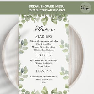 Op de afbeelding: Een sjabloon voor een vrijgezellenfeestmenu met een witte achtergrond en groene bladaccenten. Het menu bevat voorgerechten, hoofdgerechten en desserts. De tekst "BRIDAL SHOWER MENU EDITABLE TEMPLATE IN CANVA" staat bovenaan.