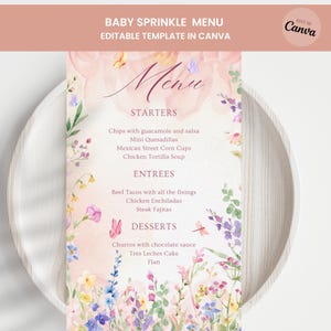 May include: A floral-themed menu for a baby sprinkle, featuring watercolor flowers in pink, purple, and blue. The menu includes starters, entrees, and desserts, with dishes like tacos, enchiladas, and churros. The text reads "BABY SPRINKLE MENU" and "EDITABLE TEMPLATE IN CANVA".