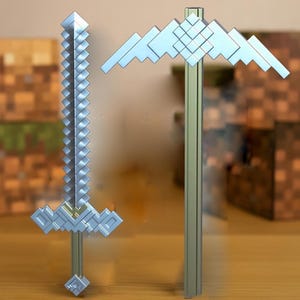 May include: A silver Minecraft sword and axe, both made in a pixelated style, are displayed on a wooden surface. The text "Minecraft Movie Sword & Axe" is printed below the objects.
