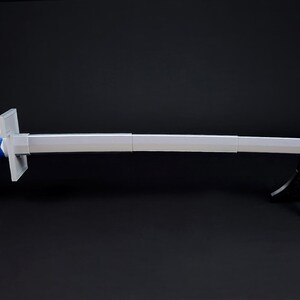 May include: A long, silver sword with a blue handle featuring white diamond-shaped accents. The sword is displayed on a black stand against a dark background. The blade is straight and has a slight curve at the tip.