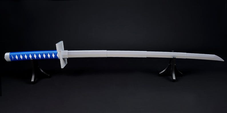 May include: A long, silver sword with a blue handle featuring white diamond-shaped accents. The sword is displayed on a black stand against a dark background. The blade is straight and has a slight curve at the tip.