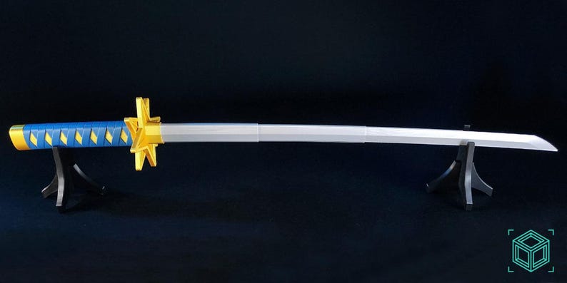 May include: A katana sword with a blue and yellow handle and a silver blade. The sword is displayed on two black stands against a dark background. The handle has a diamond pattern.