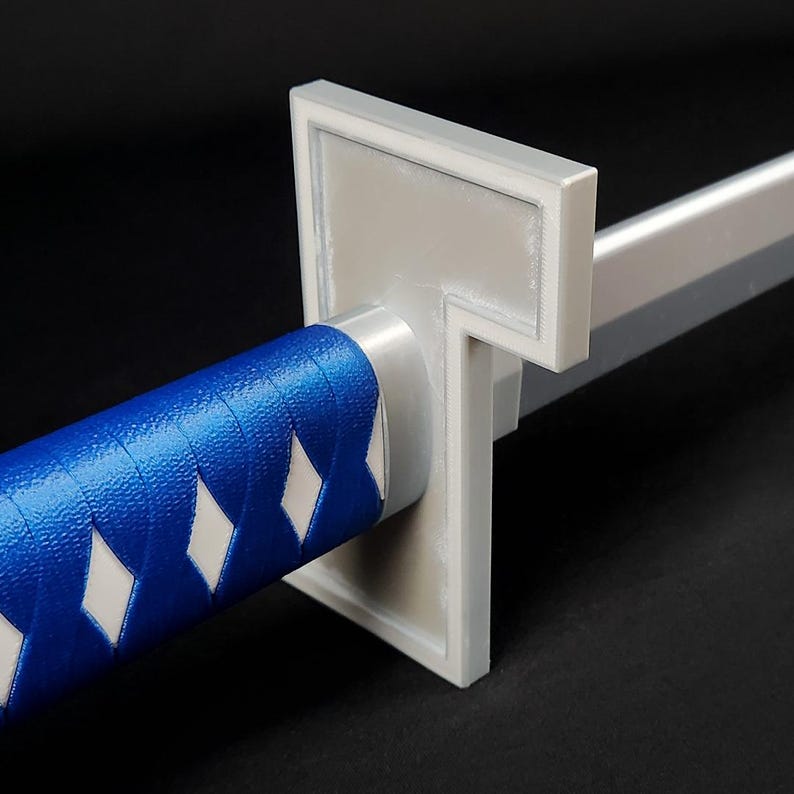 May include: Close-up of a katana sword with a blue and white handle. The handle is wrapped in blue material with white diamond-shaped accents. The guard is a light gray color, and the blade is silver.