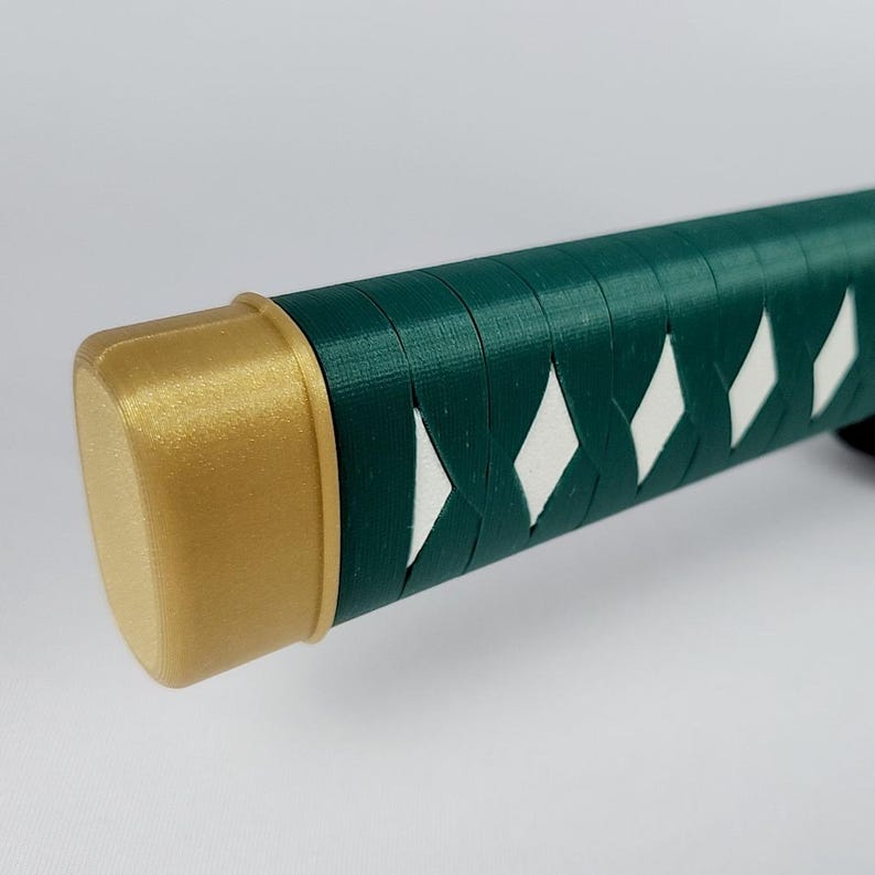 May include: A close-up of a green and gold katana handle. The handle is wrapped in a diamond pattern with white accents. The end cap is gold.