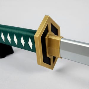May include: A close-up of a decorative sword. The handle is wrapped in dark green material with white diamond-shaped accents. The guard is gold-colored with black accents, and the blade is silver. The sword is resting on a black stand.