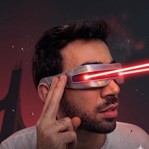Può includere: Visiera futuristica argentata con raggi laser rossi che escono dalle aperture degli occhi. La visiera ha una superficie riflettente. Lo sfondo è un design a tema spaziale scuro con accenti rossi e bianchi.