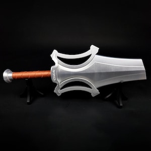 May include: A silver-colored sword with a wide, flat blade and a complex, open-work crossguard. The handle is wrapped in a textured, copper-colored material, and the pommel is a simple silver disc. The sword is displayed horizontally.