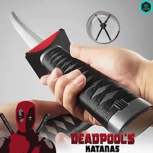 May include: A black and silver katana with a red accent, held in a hand. The handle has a textured grip. The text "DEADPOOL'S KATANAS" is visible. A Deadpool graphic is in the lower left corner.