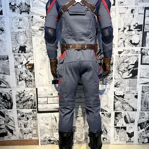 May include: A blue and red superhero costume with a brown leather belt and black boots. The costume has a detailed design with a star on the chest and a red and blue pattern on the arms and legs.
