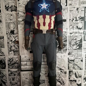 May include: A blue and red superhero costume with a large star on the chest. The star is lit up with blue lights. The costume includes a belt, pants, and boots.