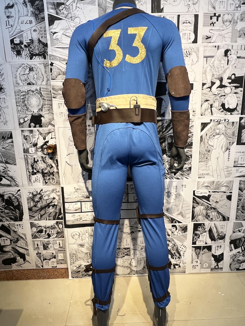 May include: A blue jumpsuit with brown leather accents and a gold number 33 on the back. The jumpsuit has a brown belt with a pouch on the front. The jumpsuit is on a mannequin.