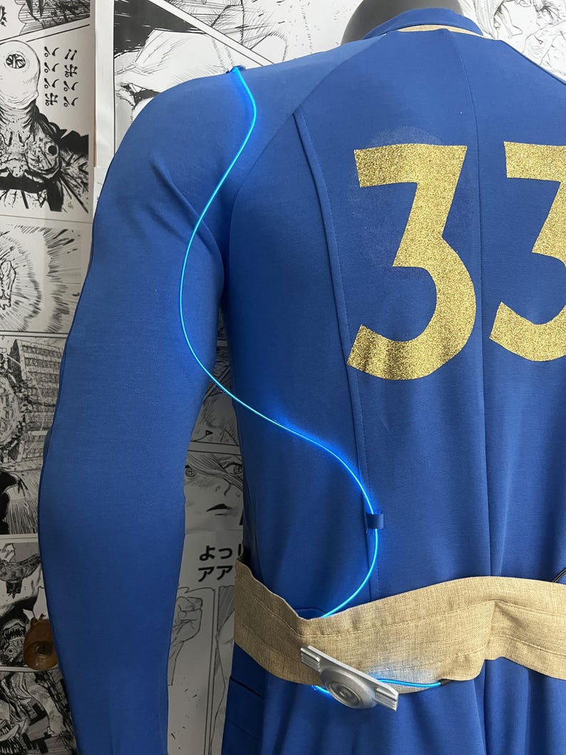May include: A blue jumpsuit with a gold number 33 on the back. A blue glowing wire is attached to the jumpsuit and wraps around the wearer's torso. The jumpsuit has a tan fabric belt with a silver buckle.