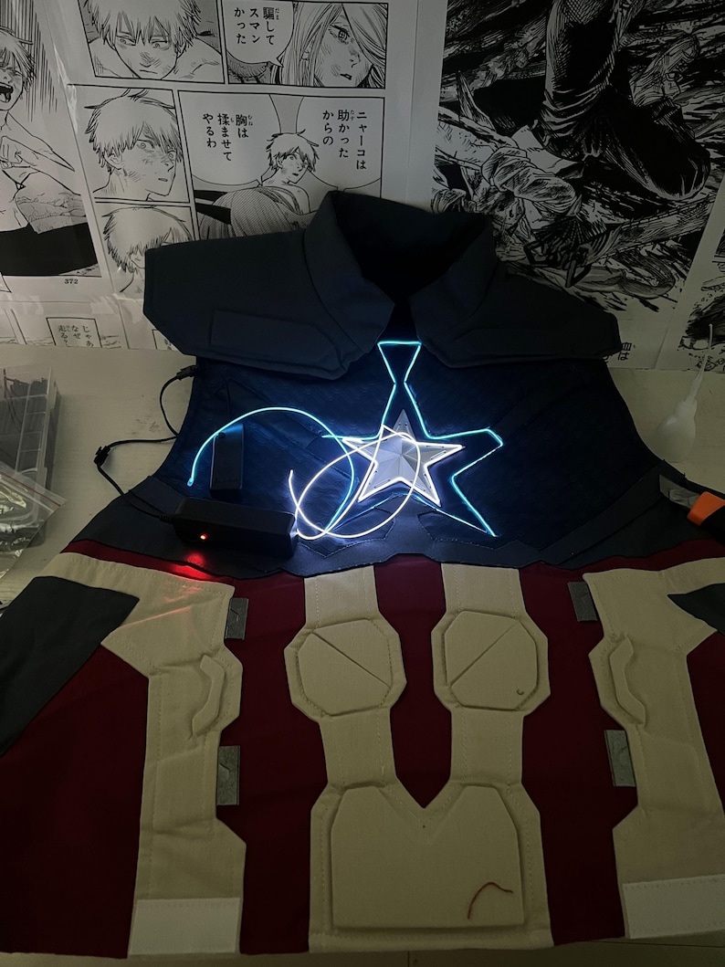 May include: A blue and red costume with a white star on the chest. The star is lit up with blue light. The costume is made of fabric and has a padded chest piece.