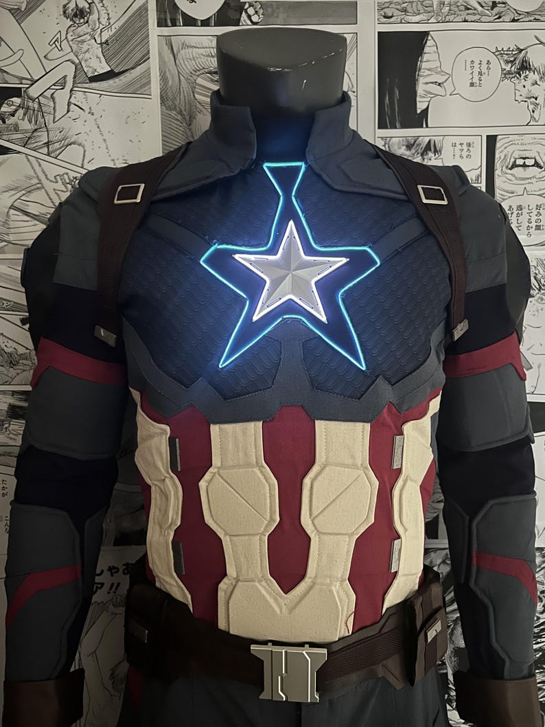 May include: A blue and red superhero costume with a white star on the chest. The star is illuminated with a blue light. The costume has a brown belt and a black and gray design on the arms.