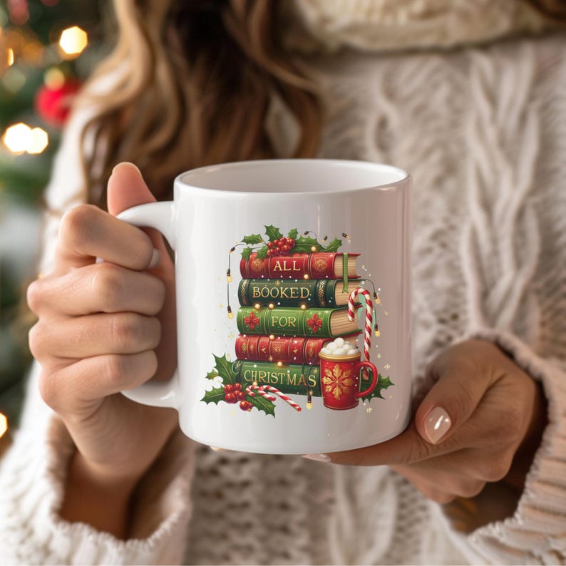 May include: White ceramic mug featuring a stack of books with the words "ALL BOOKED FOR CHRISTMAS." The books are red and green, decorated with holly and berries. A red mug with a gold design and a candy cane complete the festive design.