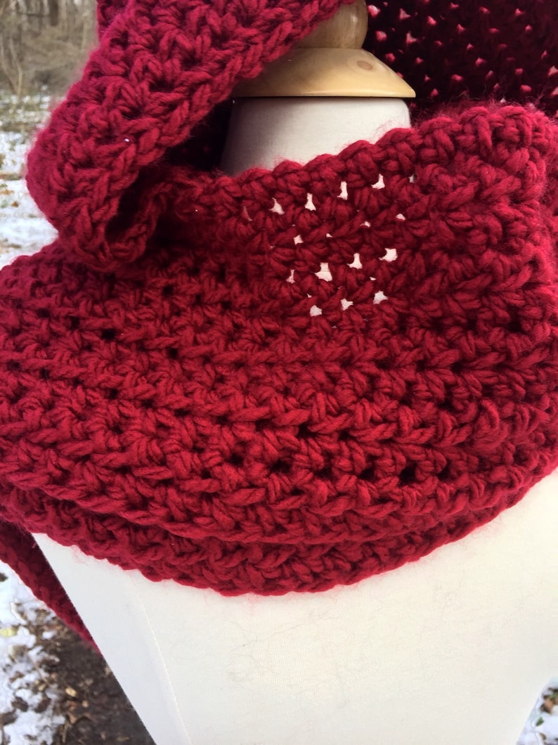 May include: A red crocheted cowl with a hood. The cowl is made with a simple stitch pattern and has a soft, cozy feel.