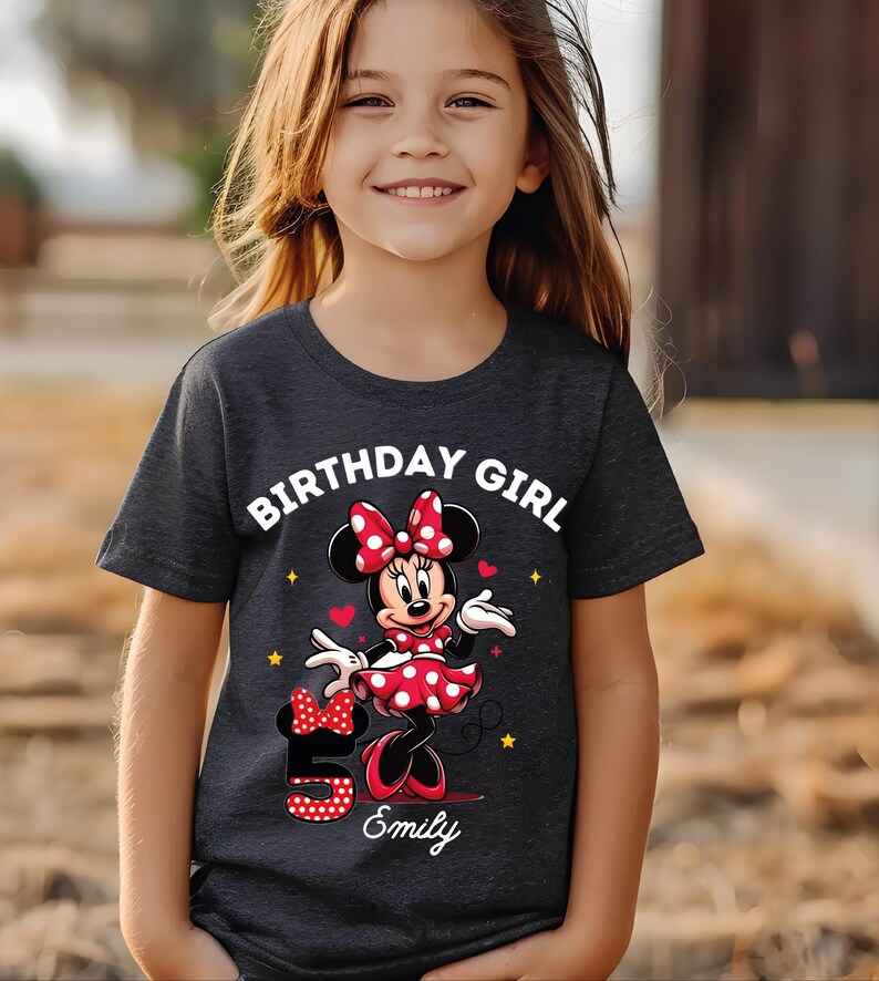 A young girl wearing a black t-shirt with a Minnie Mouse design and the text "Birthday Girl Emily" printed on it.